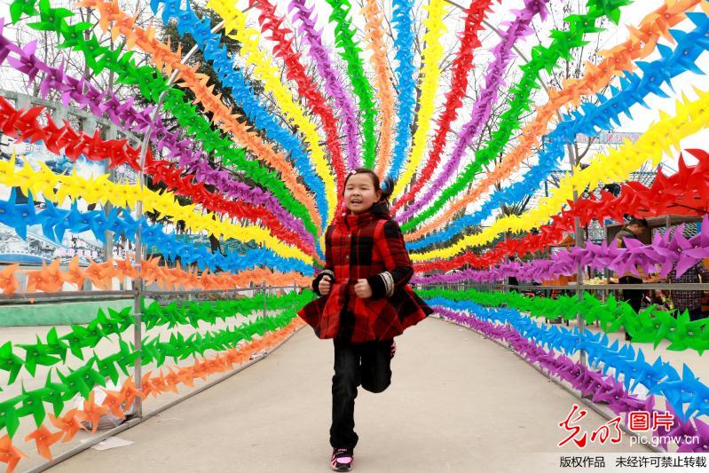 2017年03月12日,一名淮安小女孩在风车长廊中奔跑。 江苏淮安首届七彩风车节在樱花园举行。数万只色彩艳丽、造型各异的风车,营造出梦幻般的童话世界,为市民呈现了一场视觉盛宴。(侯育永摄/光明图片)