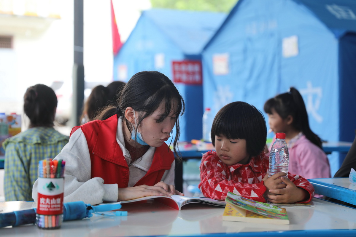 9月9日，在四川省石棉县王岗坪乡安置点内，志愿者在给小朋友讲故事。新华社记者 刘琼 摄